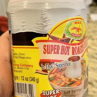 a hand holding a jar of super hot roast