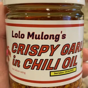 a hand holding a jar of crispy garlic oil