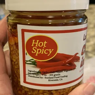 a hand holding a jar of hot spicy