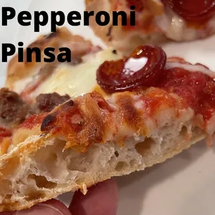 a hand holding a slice of pepperoni pizza