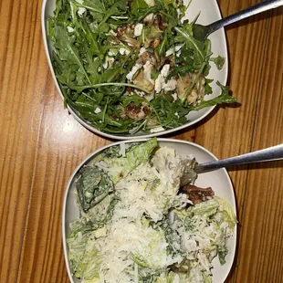 two bowls of salad on a wooden table