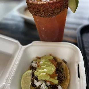 Carne asada taco with habanero sauce and a Michelada with cucumber Chamoy rim