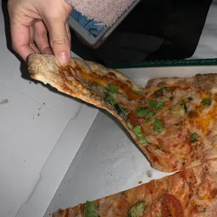 a person taking a slice of pizza