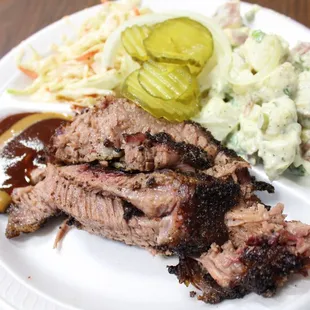 a plate of meat, coleslaw and pickles