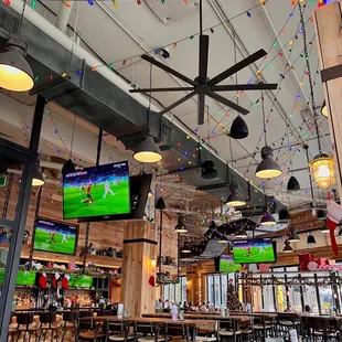 a sports bar with multiple televisions hanging from the ceiling