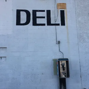 a pay phone and a deli sign