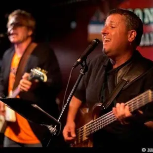 a man playing a guitar and singing into a microphone