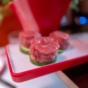 a tray of raw meat and cucumbers