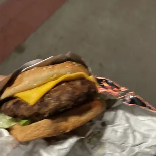 a hamburger with cheese and lettuce in a wrapper