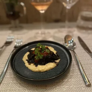 Squid ink with pasta atop polenta topped with fabulous micro greens