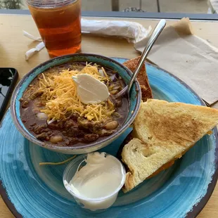 Chili and half a grilled cheese sandwich.