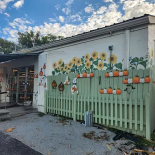 a painted fence with sunflowers and pumpkins