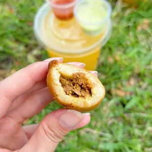 a hand holding a pastry with a bite taken out of it