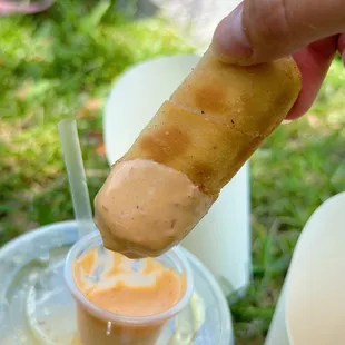 a person dipping a hot dog