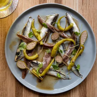 a plate of sardines and peppers on a wooden table