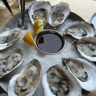a platter of oysters with a dipping sauce