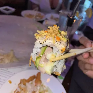 a person holding a piece of sushi