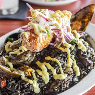Paella Pisco Bar ($32) paella w/ calamari ink sauce w/ mixed seafood, chicken, sausage, &amp; ají amarillo aioli topped w/ crispy fish