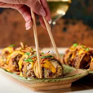 a person holding chopsticks over a plate of food