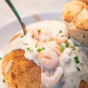 Clam chowder in a bread bowl with shrimp on top