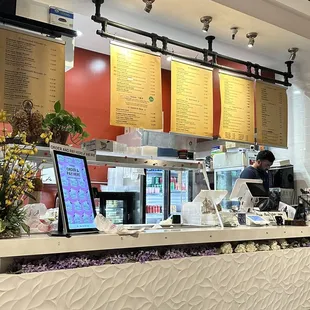 a restaurant counter with menus on the wall