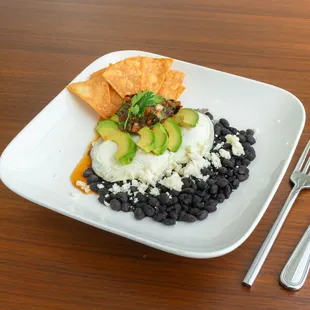 Pistachio's Huevos Rancheros served on a bed of black beans and house made char-grilled tomato salsa.