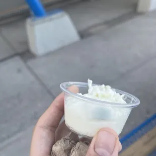 a hand holding a cup of ice cream