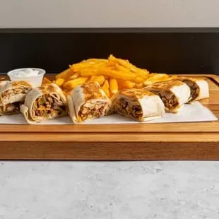 a burrito and fries on a cutting board