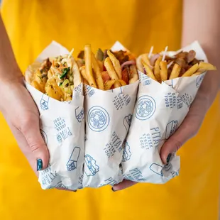 a person holding three pitas wrapped in paper