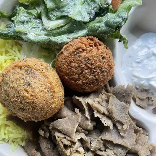 Gyro plate with tzatziki sauce and 2 falafel to go! It also comes with a pita bread that is rolled in foil (not pictured).