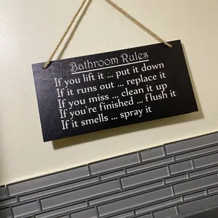 a bathroom rules sign hanging on a wall