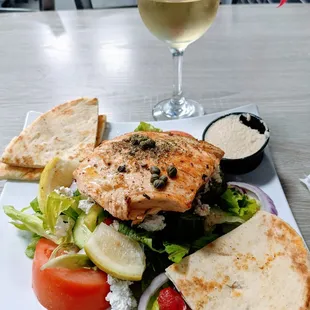 Small house Greek salad with salmon and a glass of retsina (2,000 year old traditional Greek wine)