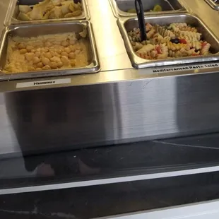 Hummus, pasta salad and more in refrigerated basins in the open kitchen.