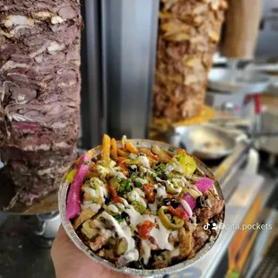 a hand holding a pita filled with meat and vegetables