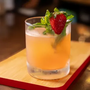 a drink in a glass on a wooden tray
