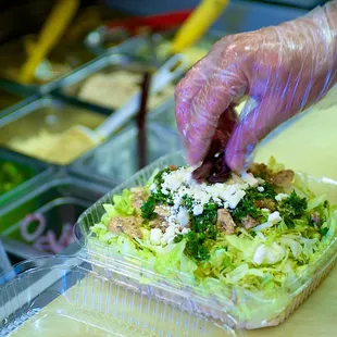 a person putting toppings on a salad