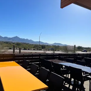 tables and chairs on a patio with mountains in the background