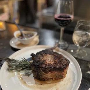 a steak on a plate with a sprig of rosemary