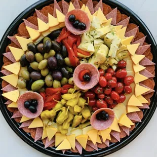 a platter of cheese, olives, and ham