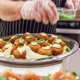 a chef putting sauce on a platter of appetizers