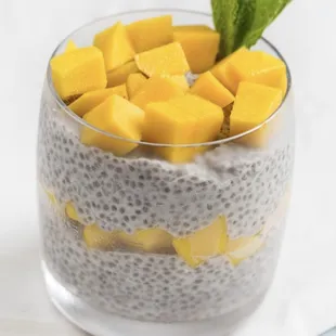a glass of chia pudding with mango slices