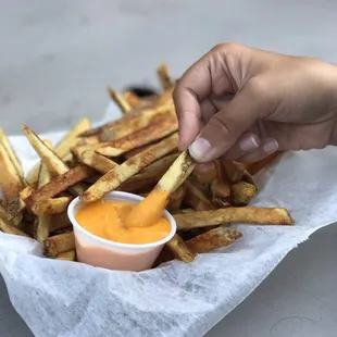 a hand dipping fries
