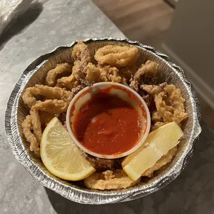 a plate of deep fried shrimp with a side of tomato sauce