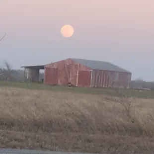 a full moon rising over a farm