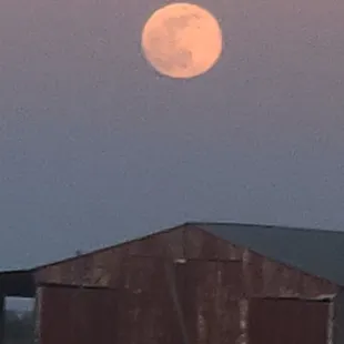 a full moon rising over a farm