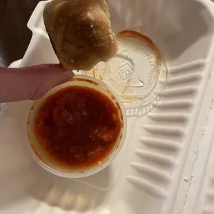  a person dipping sauce on a piece of bread