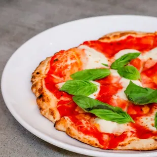 a plate of pizza with basil leaves