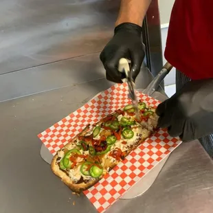 a person cutting a piece of pizza