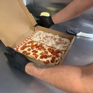 a man opening a box of pepperoni pizza