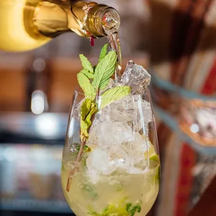 a person pouring a drink into a glass